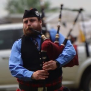 Photo of Sebastien Love wearing highland regalia and playing the bagpipes